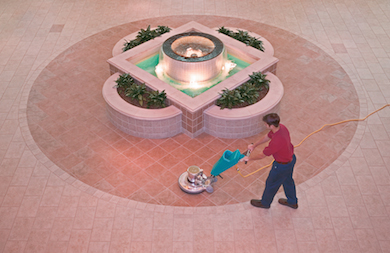 Man cleaning tiles near a fountain