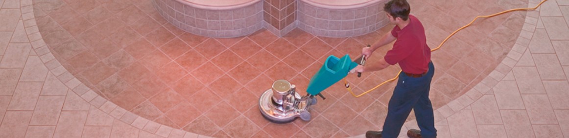 man cleaning tile floor with machine