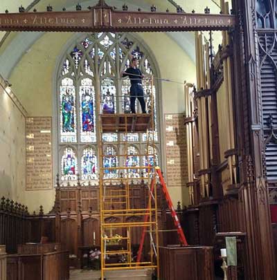 man on ladder cleaning walls in cathedral