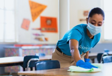 A ServiceMaster Clean expert wiping and sanitizing a table in a classroom in Mankato, Minnesota