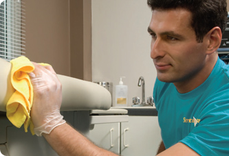 Man wiping a medical exam table with cloth