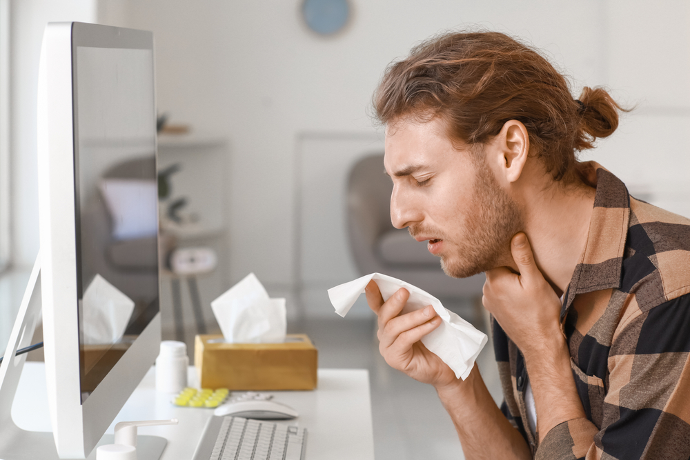 sick man at work desk with tissue