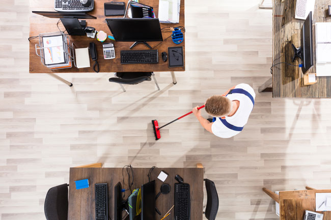man sweeping office floor