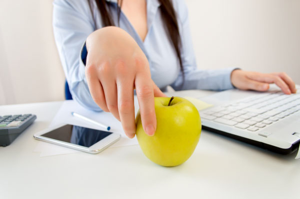 women holding an apple at a desk