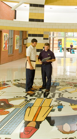 two men standing in the hallway of a school